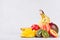 Colorful fruits mix - whole fruits and juicy sliced slices - mango, banana, pear, peach, kiwi, nectarine on white wood background.