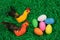 Colorful glittering Easter eggs in green artificial grass and two figures of chicken.
