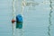 Colorful handmade buoy in deep blue sea waters on sunset. Pilotage marking maritime channel.