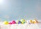 Colorful Happy Easter Eggs in Snow against Blue Sky with sunlight with room or space for copy, text, or your words. Horizontal