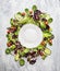 Colorful healthy salad with cucumber and tomatoes around white empty plate, on light gray wooden background, top view