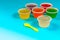 Colorful of homemade fruit gelatin mixed grain seeds in plastic cups with spoon isolated on cyan background with clipping path.