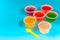 Colorful of homemade fruit gelatin mixed grain seeds in plastic cups with spoon isolated on cyan background with clipping path.