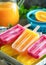 Colorful Homemade Fruit Popsicles on a Summer Day With Fresh Orange Juice in the Background