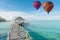 Colorful hot air balloon over Phuket beach with blue sky background, Phuket, Thailand Tropical hut and wooden bridge at holiday r