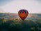 Colorful hot air balloon takes off from green park in small european city at summer sunrise