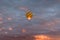 Colorful hot air balloon in yellow, orange, and dark blue colors glowing against a dramatic colorful sky and clouds at sunrise