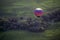 A colorful hot air balloons flies above the Iowa countryside.