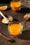 Colorful hot spicy sea buckthorn tea with cinnamon, anise and honey in glass cup on dark brown concrete background.