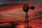 Colorful Kansas Sunset with a Windmill and tree silhouettes.