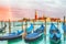 Colorful landscape with sunset sky, rainbow and gondolas parked near piazza San Marco in Venice. Church of San Giorgio Maggiore on