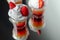 Colorful layered shots of drinks based on vodka, grenadine and orange juice decorated with whipped cream and pieces of strawberry