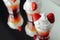 Colorful layered shots of drinks based on vodka, grenadine and orange juice decorated with whipped cream and pieces of strawberry