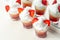 Colorful layered shots of drinks based on vodka, grenadine and orange juice decorated with whipped cream and pieces of strawberry