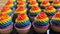 Colorful LGBTQ pride-themed cupcakes beautifully arranged on a dessert table