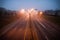 Colorful light traces of night traffic on highway. Atlanta city street, foggy autumn weather, GA, USA