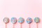 Colorful lollipops swirls on sticks in row. Striped spiral multicolored candy on pink background, top view