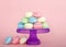 Colorful Macaron cookies on a purple pedestal pink background