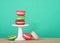 Colorful macaron cookies on a small pedestal with light green background