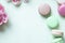 Colorful macaron or macaroon cakes and tulips on pastel green background with copy space