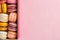 colorful macarons in the box over pink background with copy space
