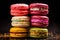 Colorful macarons stacked, dark background.