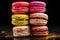 Colorful macarons stacked, dark background.