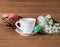 Colorful macarons with tea and flowers on wooden table.