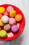 Colorful macaroons in red plate on gray wooden background