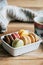 Colorful macaroons in a white box on the wooden table with a cup of hot coffee