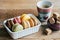 Colorful macaroons in a white box on the wooden table with a cup of hot coffee