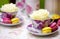 Colorful macaroons - yellow and pink - on plates with cups with white roses