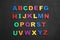 Colorful magnetic letters on black stone background. Alphabetical order