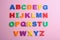 Colorful magnetic letters on pink background. Alphabetical order