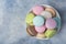 Colorful makarons in a white plate on a blue background.