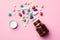 Colorful medicine pills, capsules, tablets and glass bottle on pink background