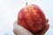 Colorful mottled apple in the hand of a man.