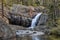 Colorful mountain waterfall into flowing stream