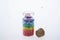 Colorful multicolor beads or tablets are poured into a glass bottle. A rainbow in a bottle. Magic pills. Macro