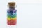 Colorful multicolor beads or tablets are poured into a glass bottle. A rainbow in a bottle. Magic pills. Macro