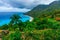 Colorful natural wild landscape with rocky mountains overgrown dense green jungle tree, palm and clear azure water of sea ocean