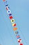 Colorful nautical sailing flags flying in the wind from the lines of a sailboat mast backlit in bright blue sky by the sun