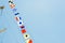 Colorful nautical sailing flags flying in the wind from the lines of a sailboat mast backlit in bright blue sky by the sun