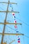 Colorful nautical sailing flags flying in the wind from the lines of a sailboat mast backlit in bright blue sky by the sun