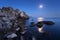 Colorful night landscape with full moon, lunar path and rocks in summer. Mountain landscape at the sea.