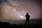 Colorful night sky with stars and silhouette of a standing man on the stone. Blue milky way with man on the mountain.