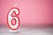 Colorful number 6 birthday cake candle on a pink background