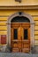 Colorful old elegant front wooden carved entrance yellow door with glass inserts, stone portal with floral ornament, picturesque