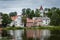 Colorful old town houses and church with lake reflection in cloudy summer day.