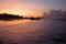 Colorful orange blue sky over the sea at sunrise. Morning sky with clouds, smooth waves and traditional fishing boat silhouette.